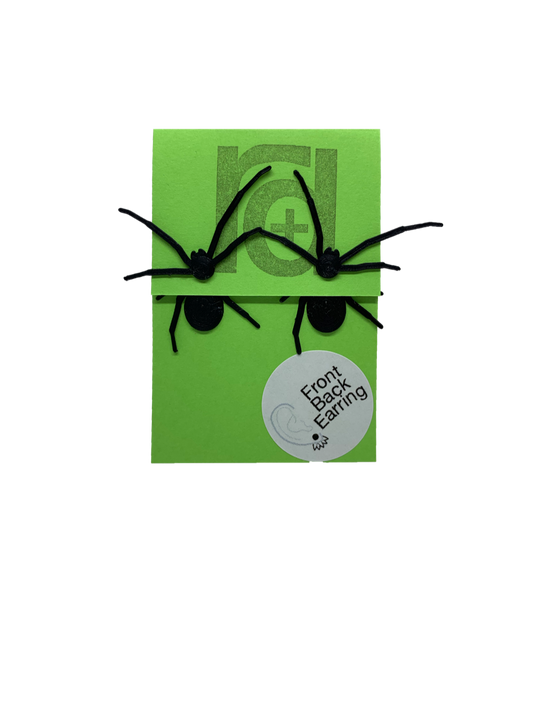 Two front back or jacket earrings are pictured on a bright green paper earring card. Each earring has two parts that are worn on each side of the earlobe. The effect is that these black long legged spiders will look as though they are crawling through your earlobe when you wear them. The front piece has two legs and the spider's head with little pinchers visible. The back piece has two more legs and a rounded black body.