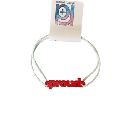 With an R+D tag, there is bracelet with a 3D printed charm. The adjustable cord on the bracelet is a white organic cotton. The charm is bright red and says proud in block letters. 
