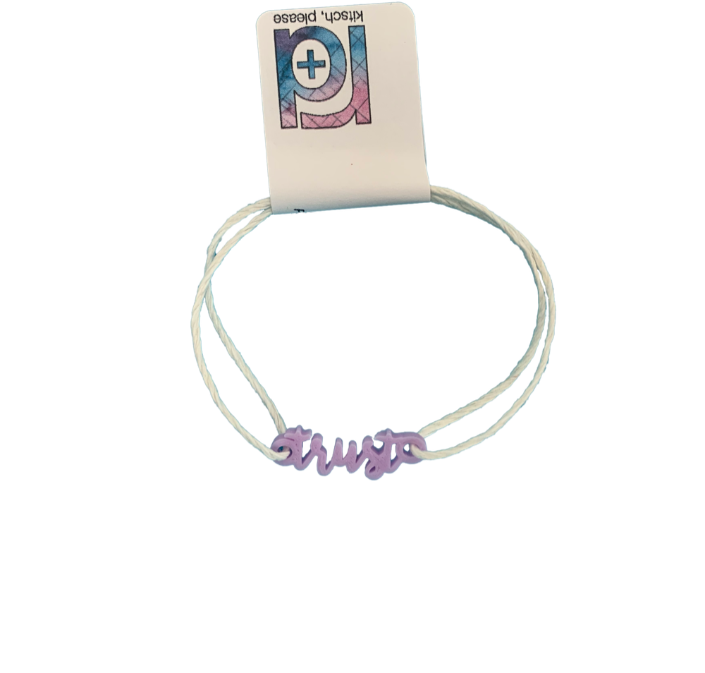 With an R+D tag, there is bracelet with a 3D printed charm. The adjustable cord on the bracelet is a white organic cotton. The charm is light purple and says trust in cursive writing.