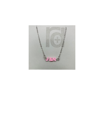 On a grey necklace card is a necklace with small letters on a metal bar. The letters are like beads and will rotate and move around. This necklace has 3 characters (J&N) in a light pink. 
