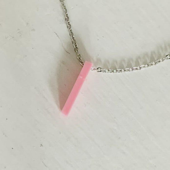 This video shows a thin 3D Printed pendant. It is a light pink pendant and a finger reaches in to push it over to the side and reveal the hidden letters: XOXO. These pendants can be customized to any word or name. 