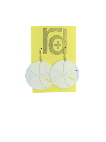 Two white earrings on a yellow earring card. The earrings look like sand dollars with a star burst patten that is raised from he surface. 