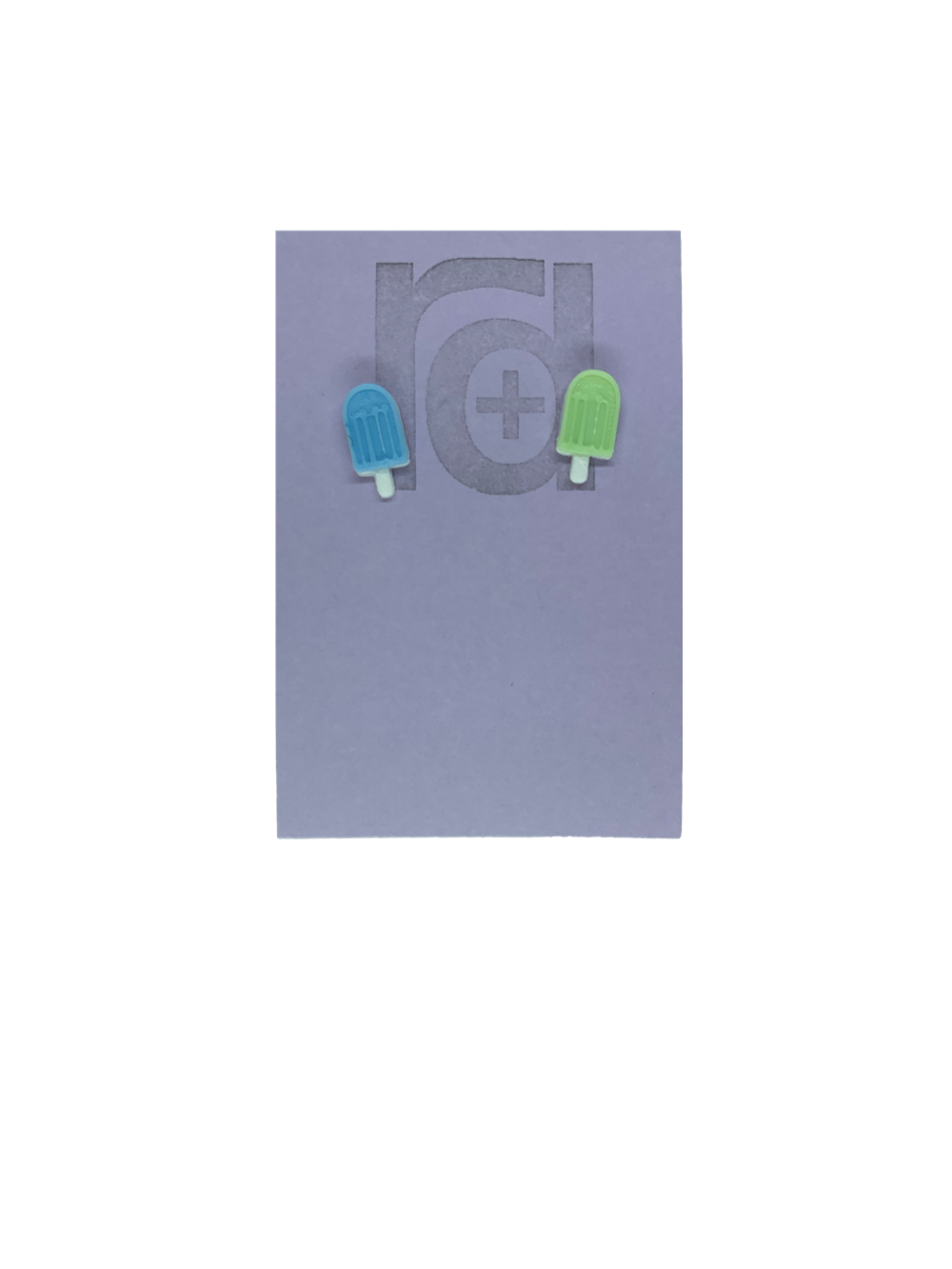 Two small and detailed R+D earrings are shown on a purple earring card. They are shaped as popsicles with white sticks. The earrings are mismatched, one popsicle is light blue and one is light mint green.