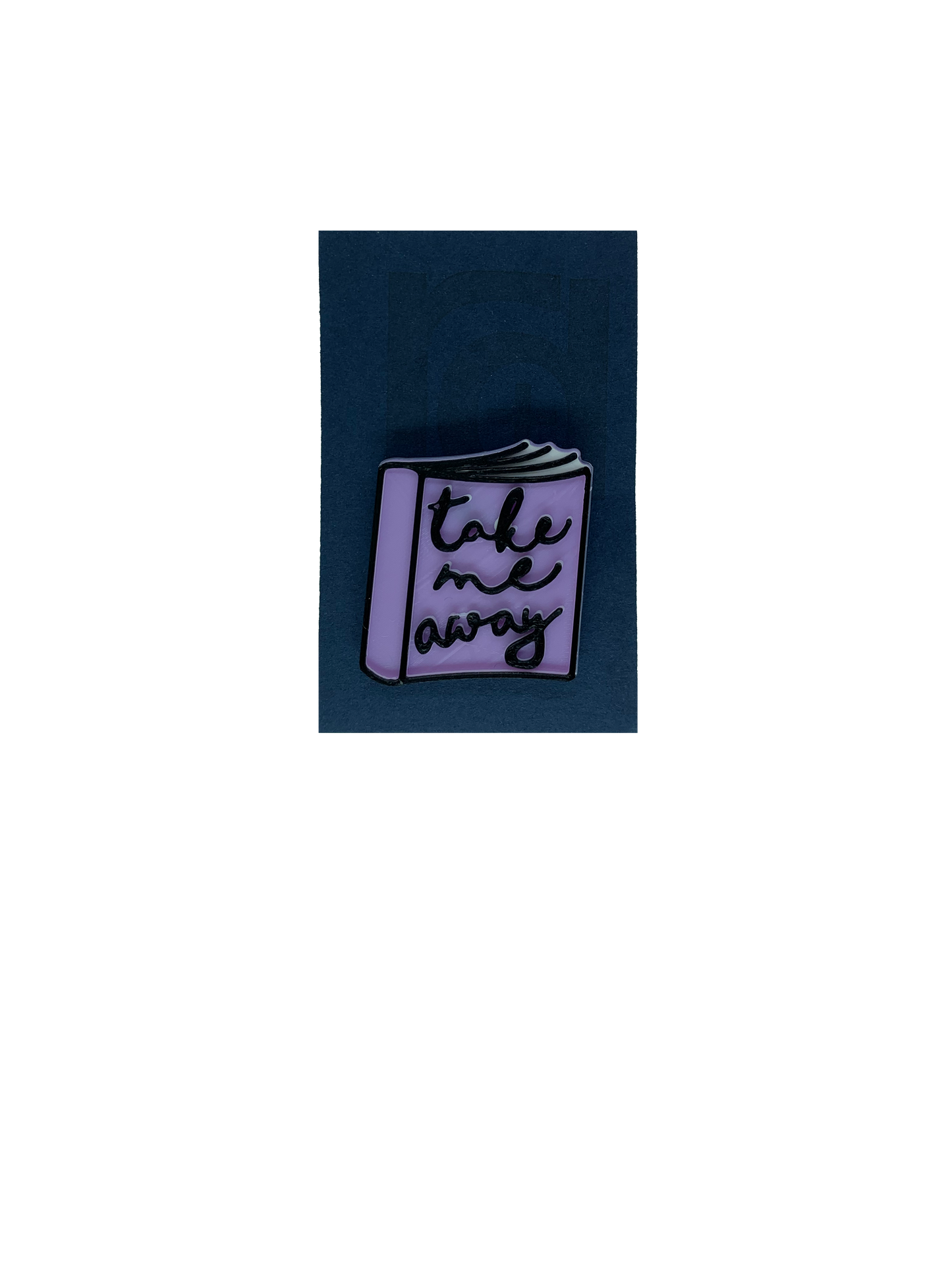 On a dark blue card is a 3D printed pin. It is the shape of a  paper back book. IThe books light purple, with white pages and has details outlined in black. On the cover, it reads, Take me away in a scripted cursive font.