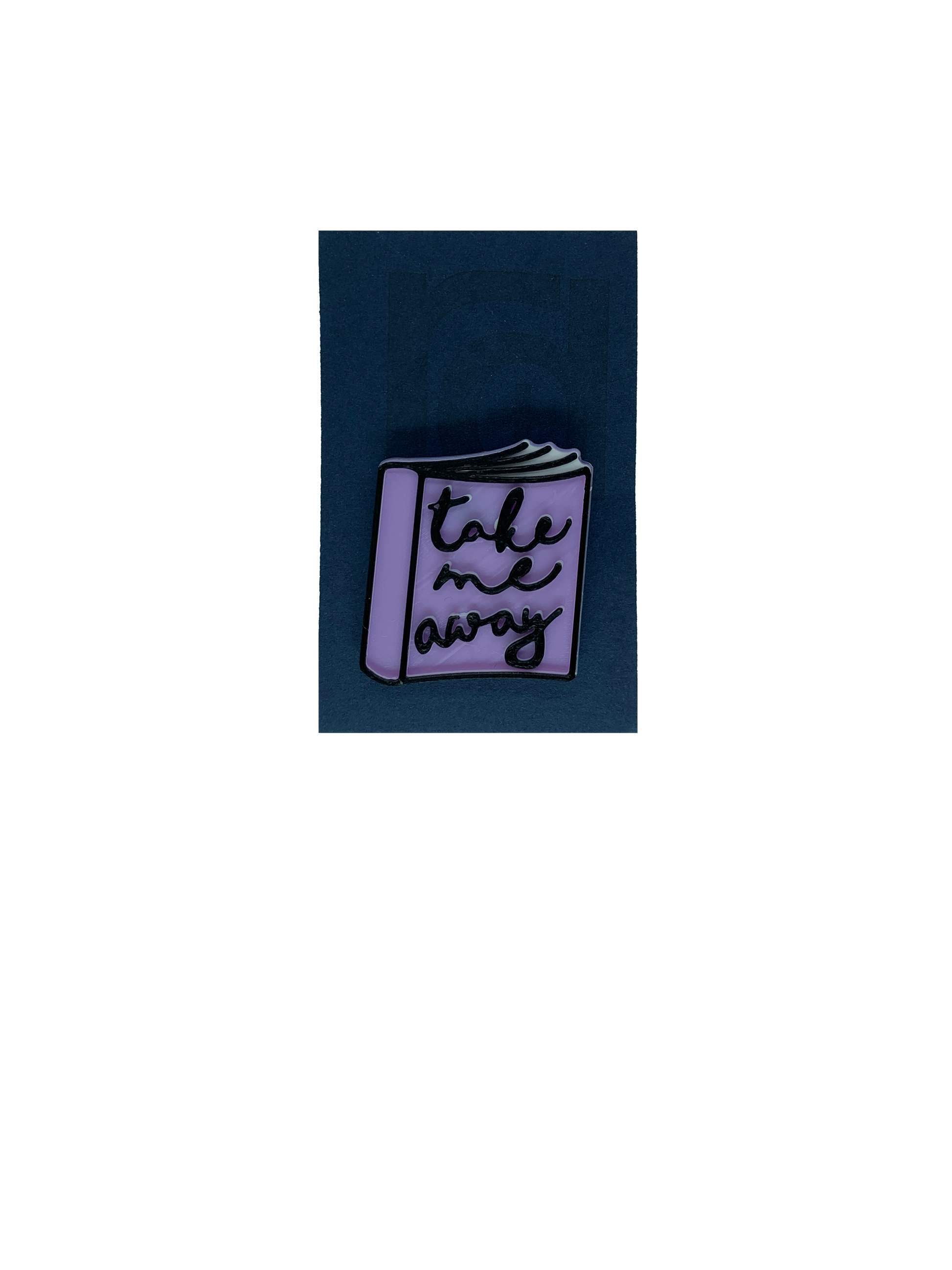 On a dark blue card is a 3D printed pin. It is the shape of a  paper back book. IThe books light purple, with white pages and has details outlined in black. On the cover, it reads, Take me away in a scripted cursive font.