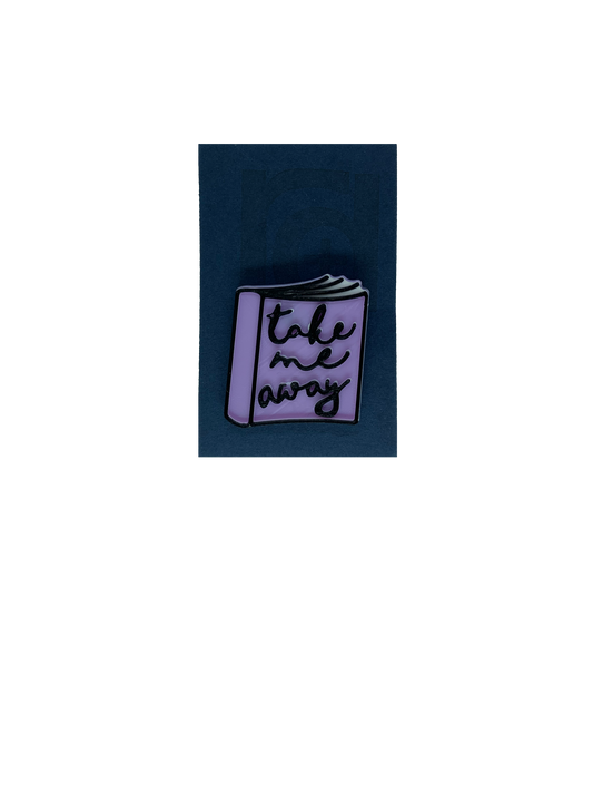 On a dark blue card is a 3D printed pin. It is the shape of a  paper back book. IThe books light purple, with white pages and has details outlined in black. On the cover, it reads, Take me away in a scripted cursive font.