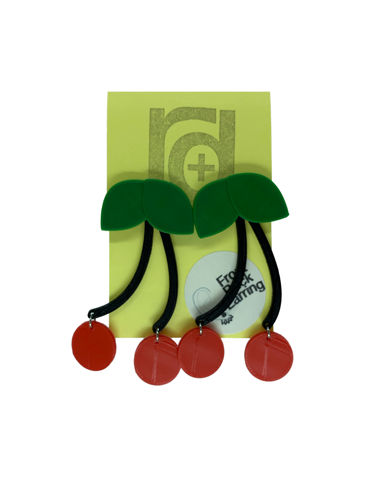 Hanging off of a yellow earring card are two statement earrings  shaped like cherries. They have green leaves that are worn on the front of the ear lobe with two black stems that lead to bright red cherries. The stem is worn behind the ear to give depth to this classic style that will match any picnic or rock a billy outfit.