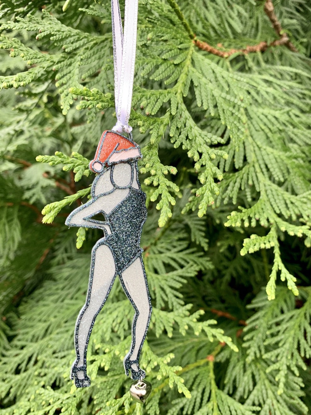 Hanging from a evergreen tree is a 3D Printed R+D ornament that looks like Beyonce from her Single Ladies video: She is posing with her hand on her hip and one leg jutting out to the side. She is wearing a red and white santa hat and a black lone shoulder leotard. She is wearing black strappy heels and a small jingle bell hangs from one of her feet. The entire ornament is covered in a shimmery glitter that will catch all the lights of your holiday celebration.