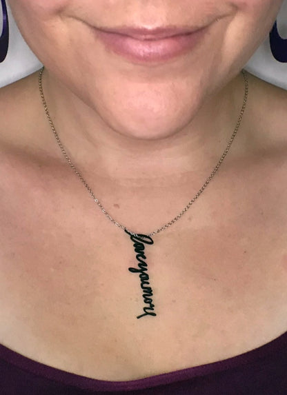 This is a close up of a necklace being worn. There is a 3D printed pendant that has the words, love you more, and is made from a handwriting sample. 
