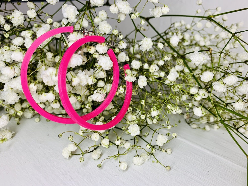 Hanging off of baby's breath flowers are two bright hot pink hoop earrings. These earrings are lightweight (light enough to hang from these delicate branches) and made from a plant based filament. 