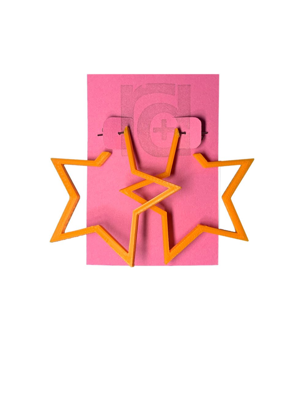 On a bright pink card are two R+D earrings. The earrings are orange star hoops that are 3D printed with a plant based filament.