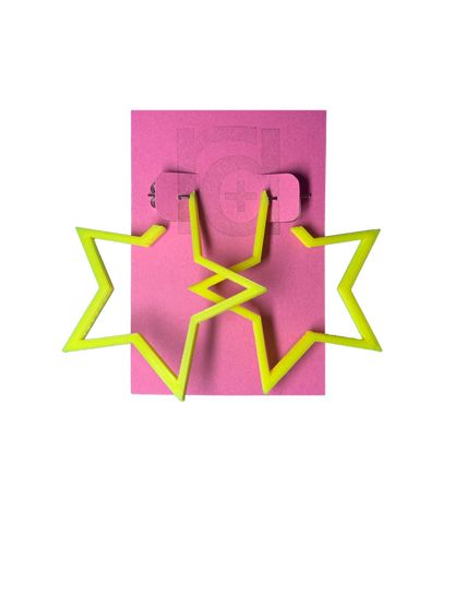 On a bright pink card are two R+D earrings. The earrings are yellow star hoops that are 3D printed with a plant based filament. 