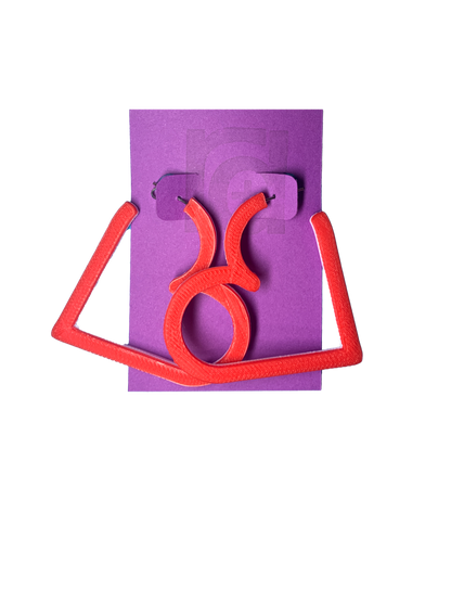 On a purple R+D card is a pair of 3D printed hoops. They are in the shape of a heart with bright red visible on the top layer. Printed with a plant based filament, there are three colors layered: red, white, and  light pink. 