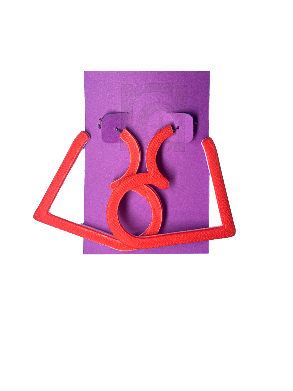 On a purple R+D card is a pair of 3D printed hoops. They are in the shape of a heart with bright red visible on the top layer. Printed with a plant based filament, there are three colors layered: red, white, and  light pink. 