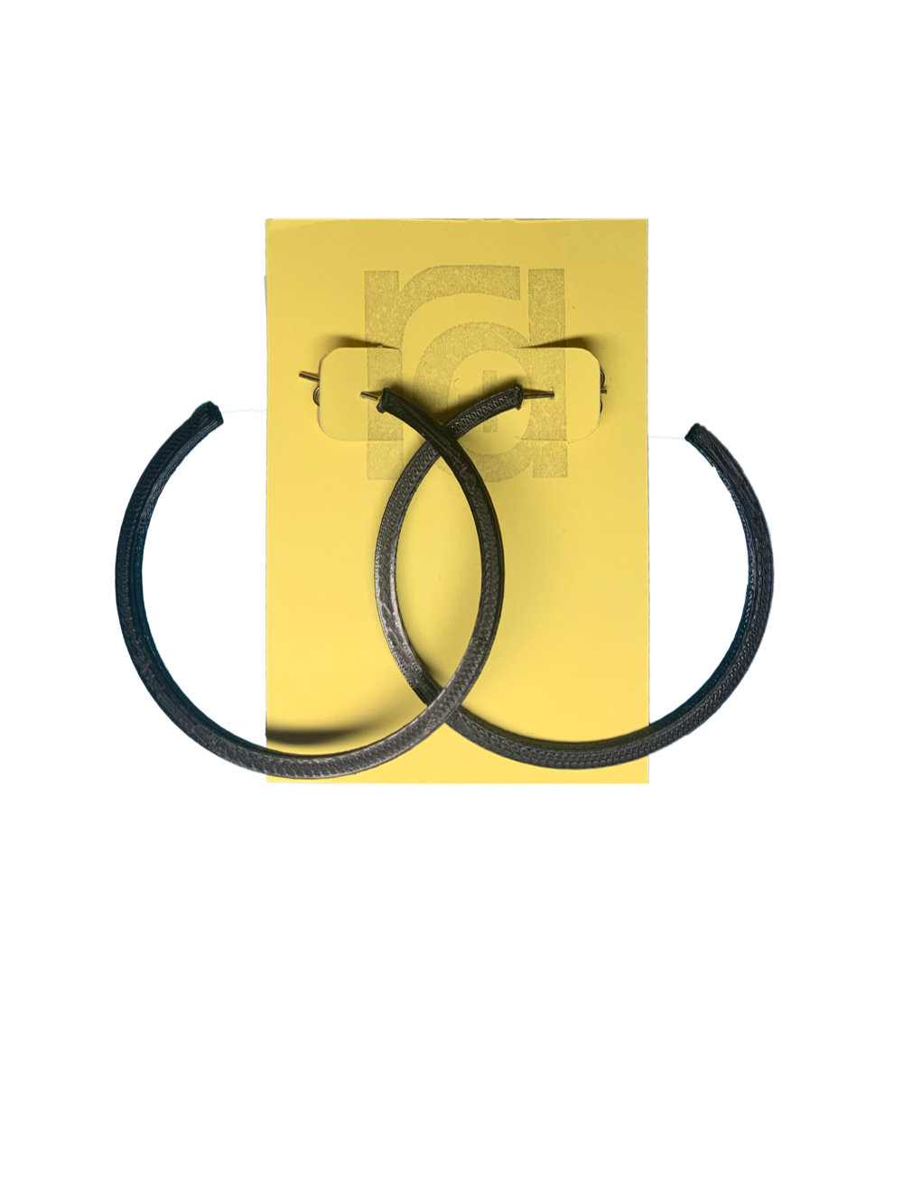 Shown on a yellow R+D card are two 3D printed hoop earrings. They are large two inch hoops in a black that are lightweight and plant based.