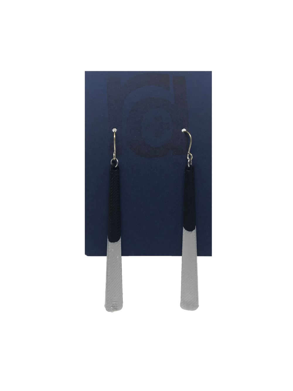 Shown on a sustainable dark blue earring card, these earrings are long dangles that flare out slightly. The black plant based earring is dipped into metallic silver paint to give a perfect shimmering accent.