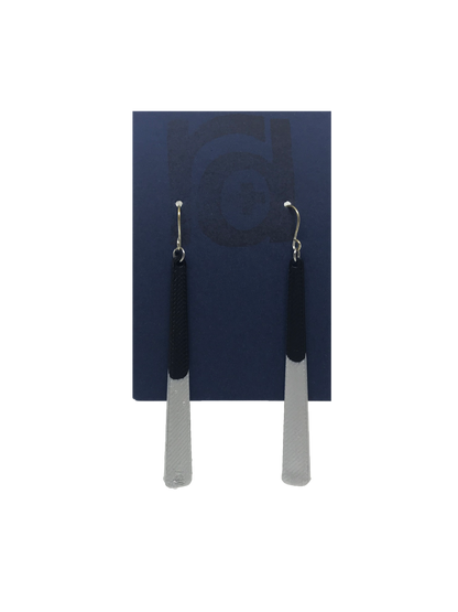 Shown on a sustainable dark blue earring card, these earrings are long dangles that flare out slightly. The black plant based earring is dipped into metallic silver paint to give a perfect shimmering accent.