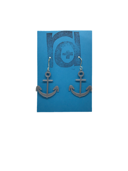 Two earrings hang on a blue earring card. The earrings are 3D printed in a plant based silver filament. They are shaped like anchors. 