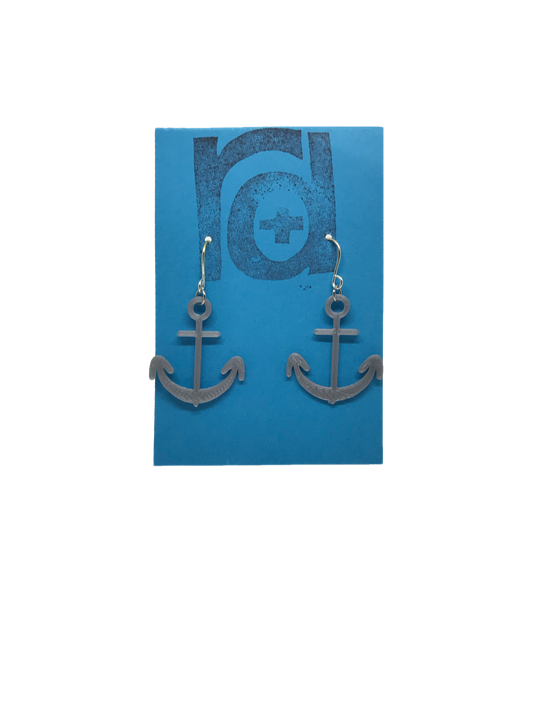 Two earrings hang on a blue earring card. The earrings are 3D printed in a plant based silver filament. They are shaped like anchors. 
