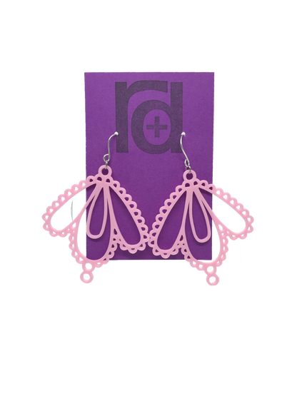 Two earrings on a purple earring card: they have three teardrop shapes and are reminiscent to lace. These 3D printed earrings are made with a light pink sustainable filament.