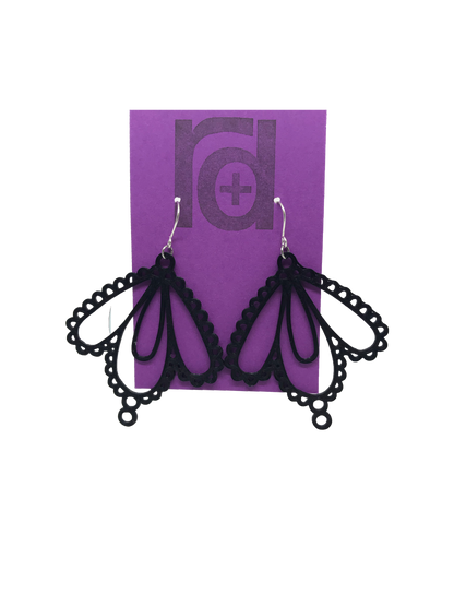 Two earrings on a purple earring card: they have three teardrop shapes and are reminiscent to lace. These 3D printed earrings are made with a black sustainable filament.  