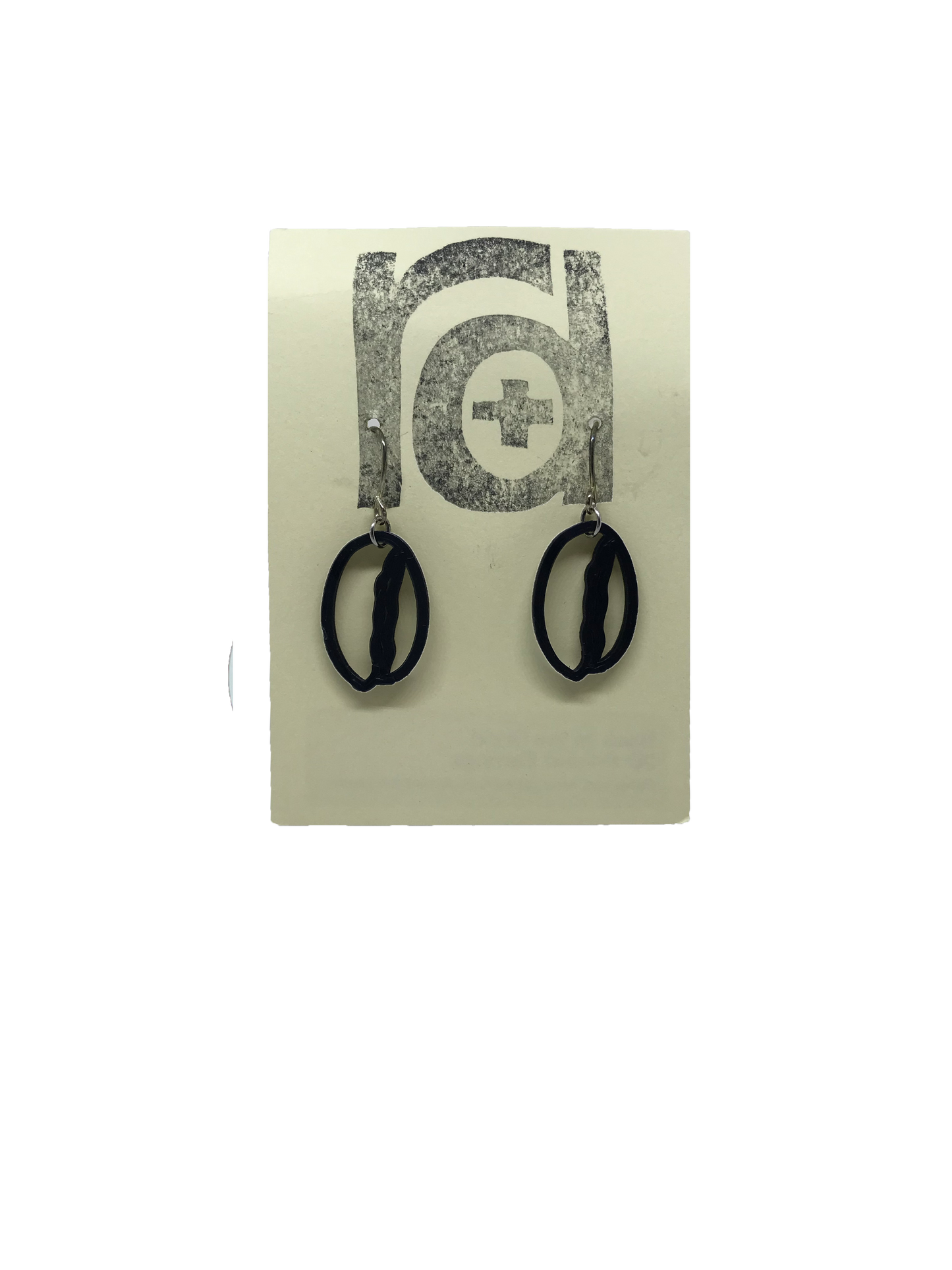 Shown on a light tan earring card are two earrings that are shaped like coffee beans. 
