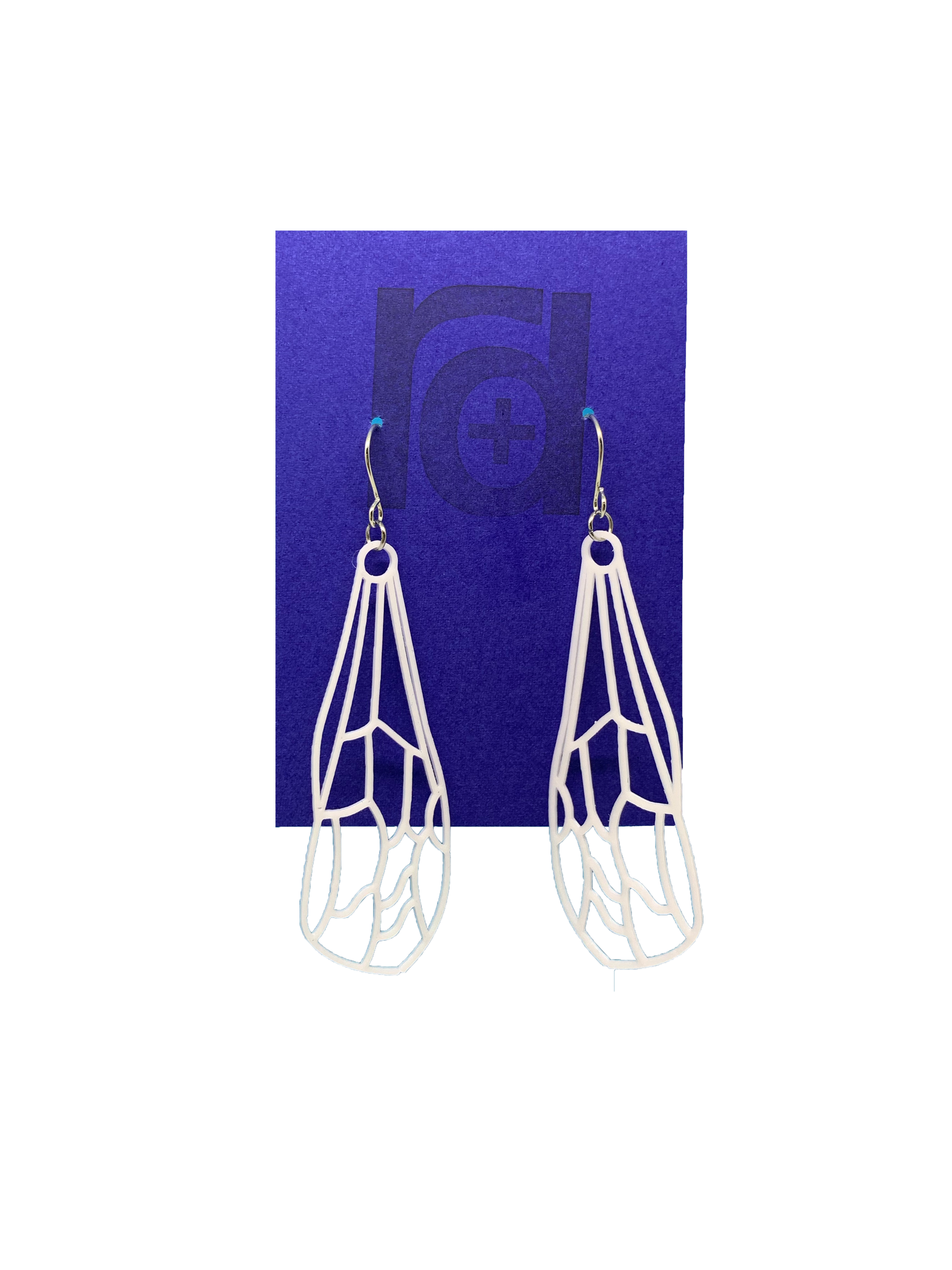 Hanging off of a bright blue earring card are two earrings. They are white and show a delicate wing of a dragonfly or insect with all the veins.