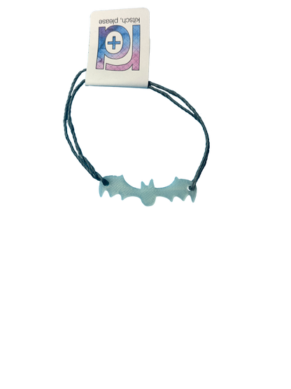 Pictured on a transparent background is a bracelet. There are two dark grey strands and they are holding on to a 3D printed bat that glows in the dark. Hidden by a R+D tag are the two adjustable knots.