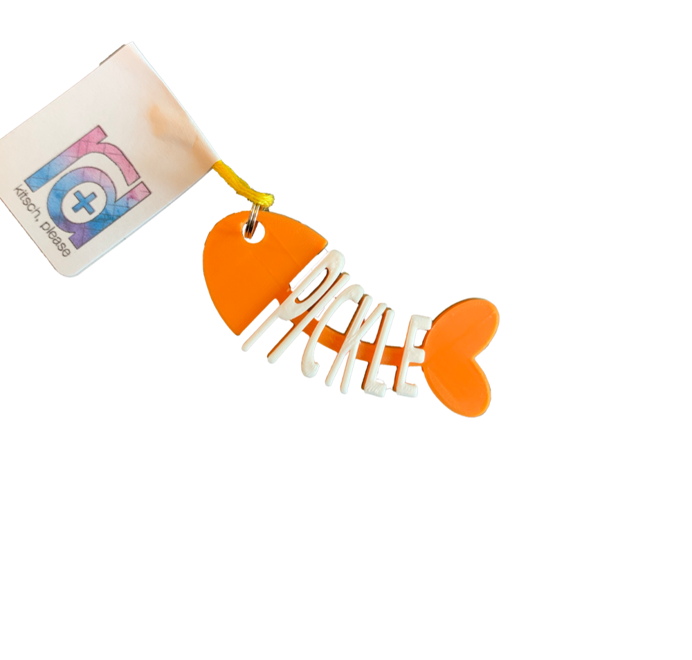 There is a cat tag that is shaped like a cartoon fish that has been eaten. The head, tail, and backbone is bright orange.  Where the bones would be, there are letters to  form the name Pickle in white. 