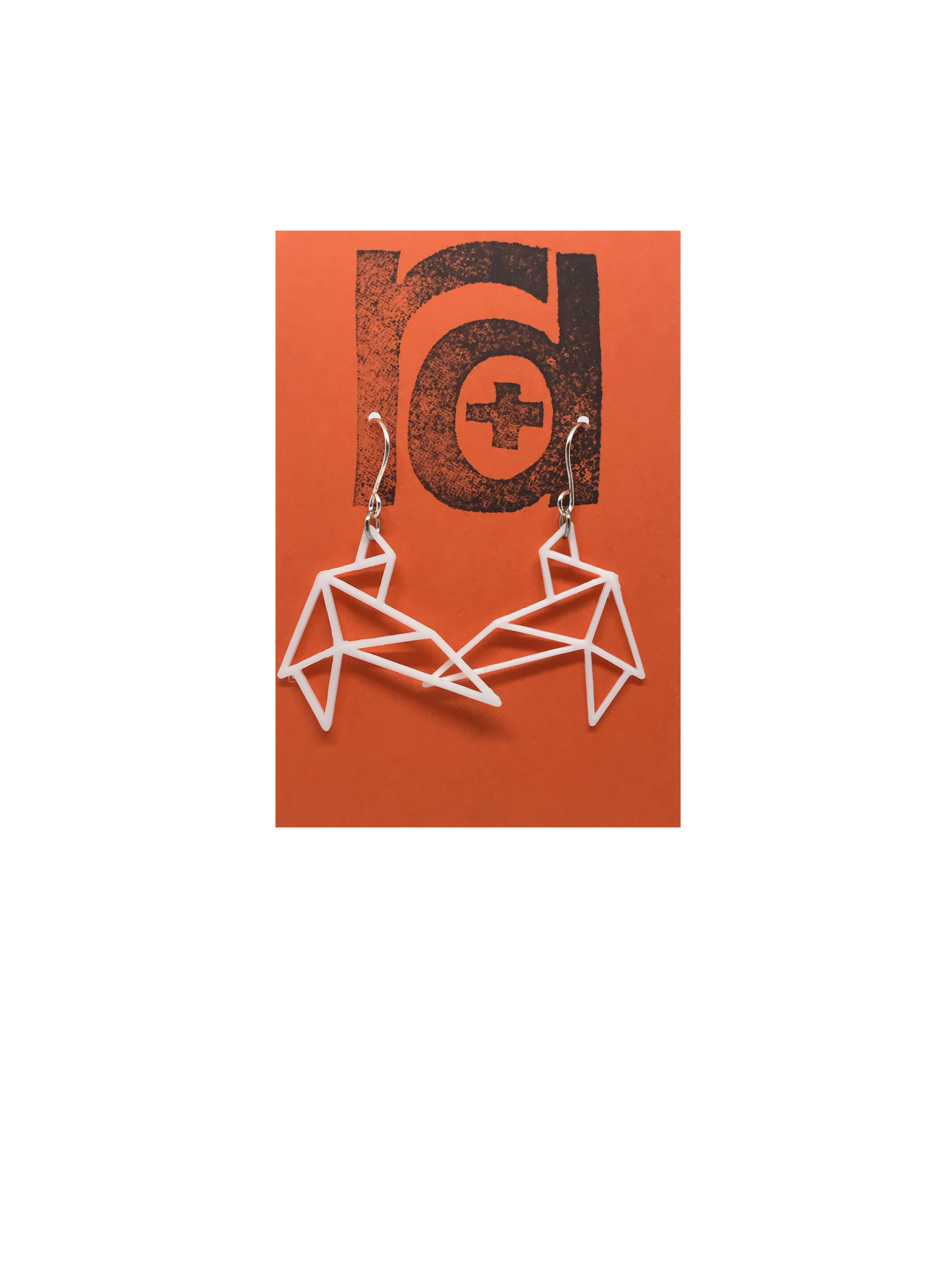 Shown on a bright orange earring card are two R+D earrings. They are geometric line shapes of birds flying. These sustainable 3D printed earrings are printed in white.