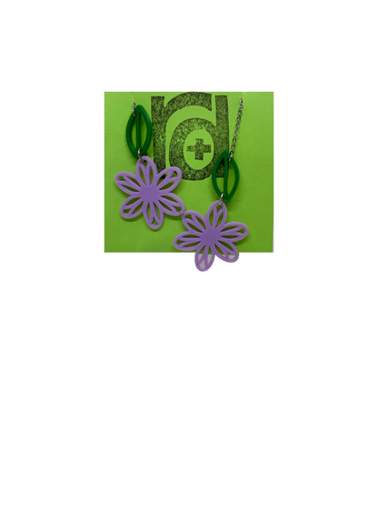 On a bright green necklace card is a asymetrical necklace with two light purple flower blossoms and two kelly green leaves. 
