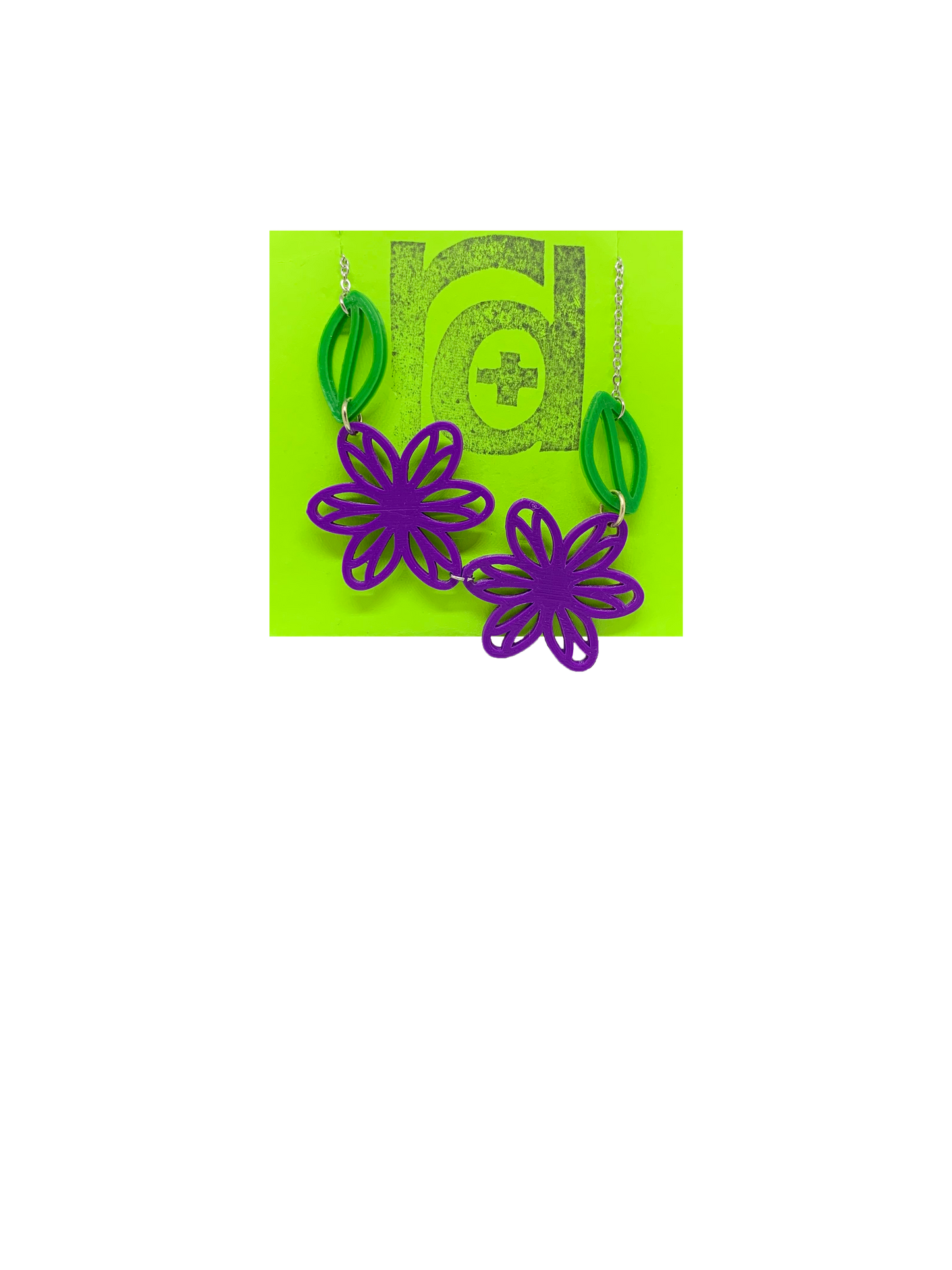 On a bright green necklace card is a asymetrical necklace with two purple flower blossoms and two kelly green leaves.