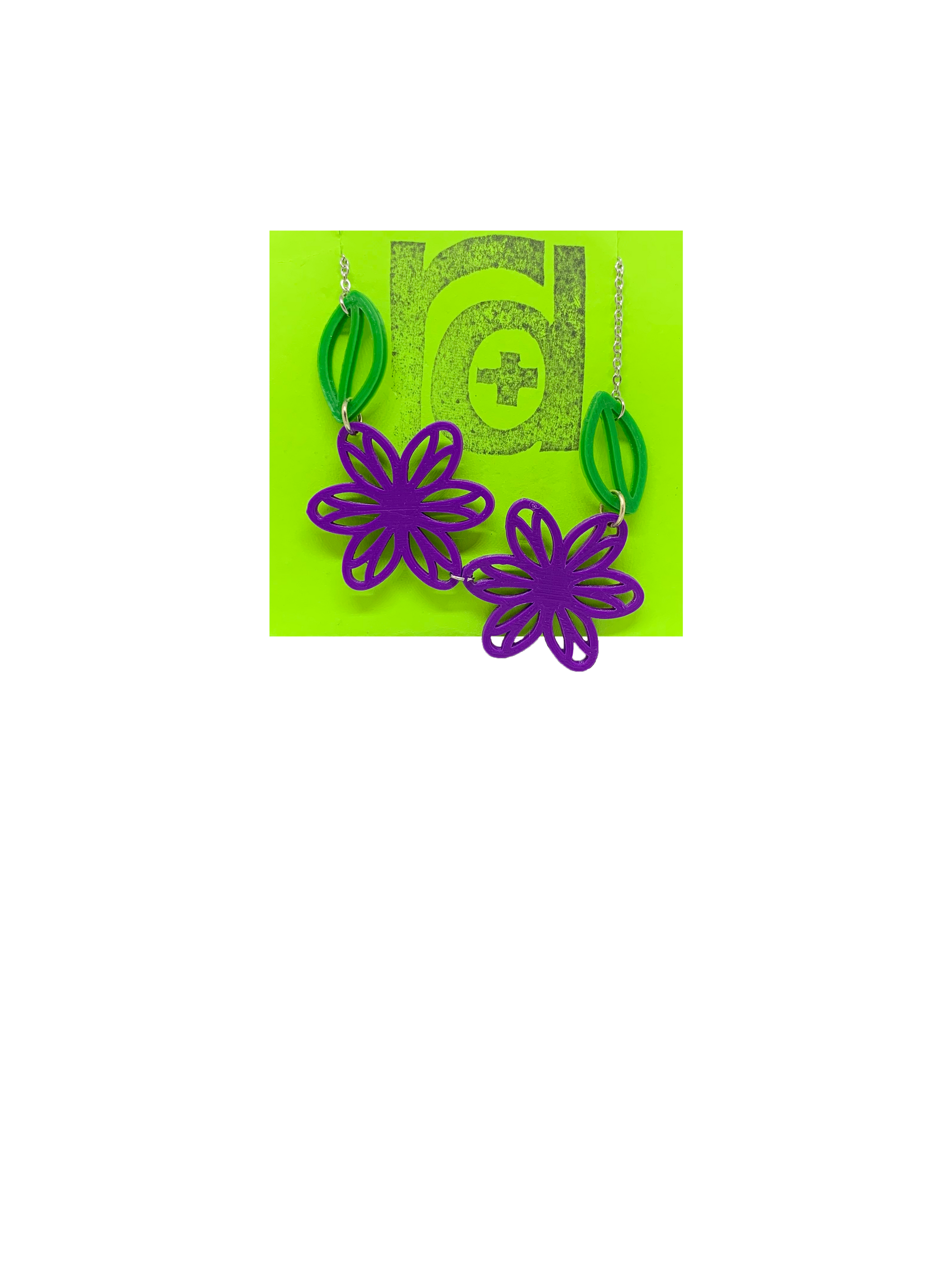 On a bright green necklace card is a asymetrical necklace with two purple flower blossoms and two kelly green leaves.