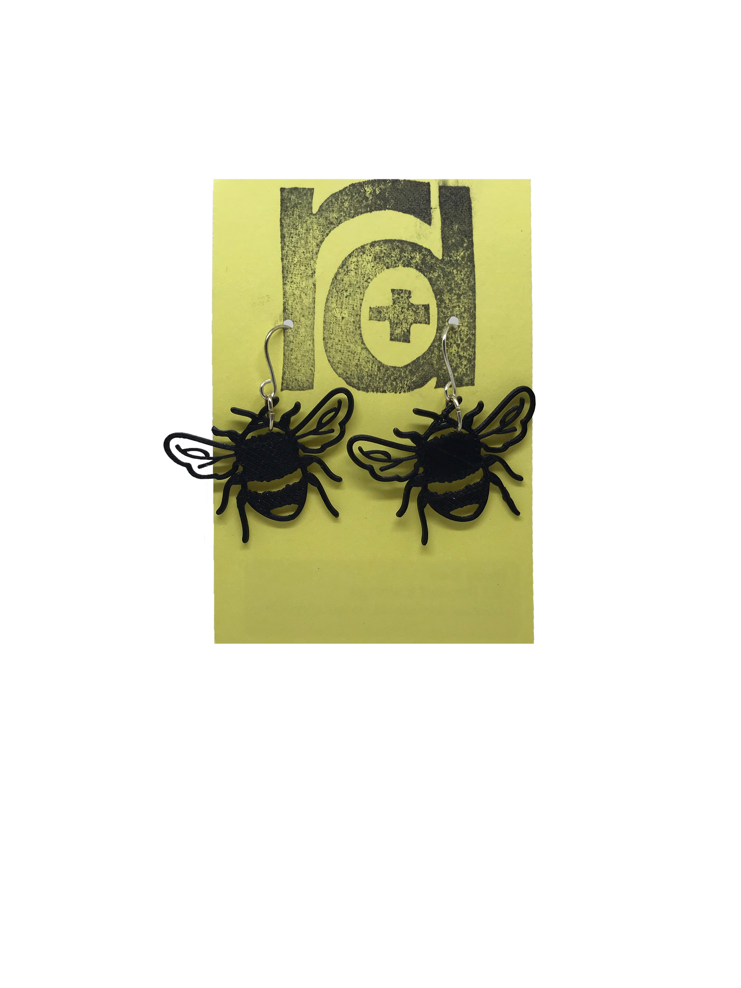 On a muted yellow card are two R+D earrings. They are shaped like bumble bees straight on; they have delicate veins in the wings and the body includes the quintessential stripes of a bee that are fuzzy for collecting pollen.