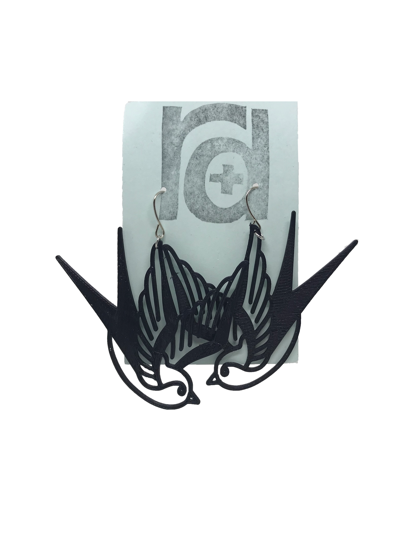 On a light blue earring card are two R+D earrings. They are black and look like two swallow birds that are circling or flying down.