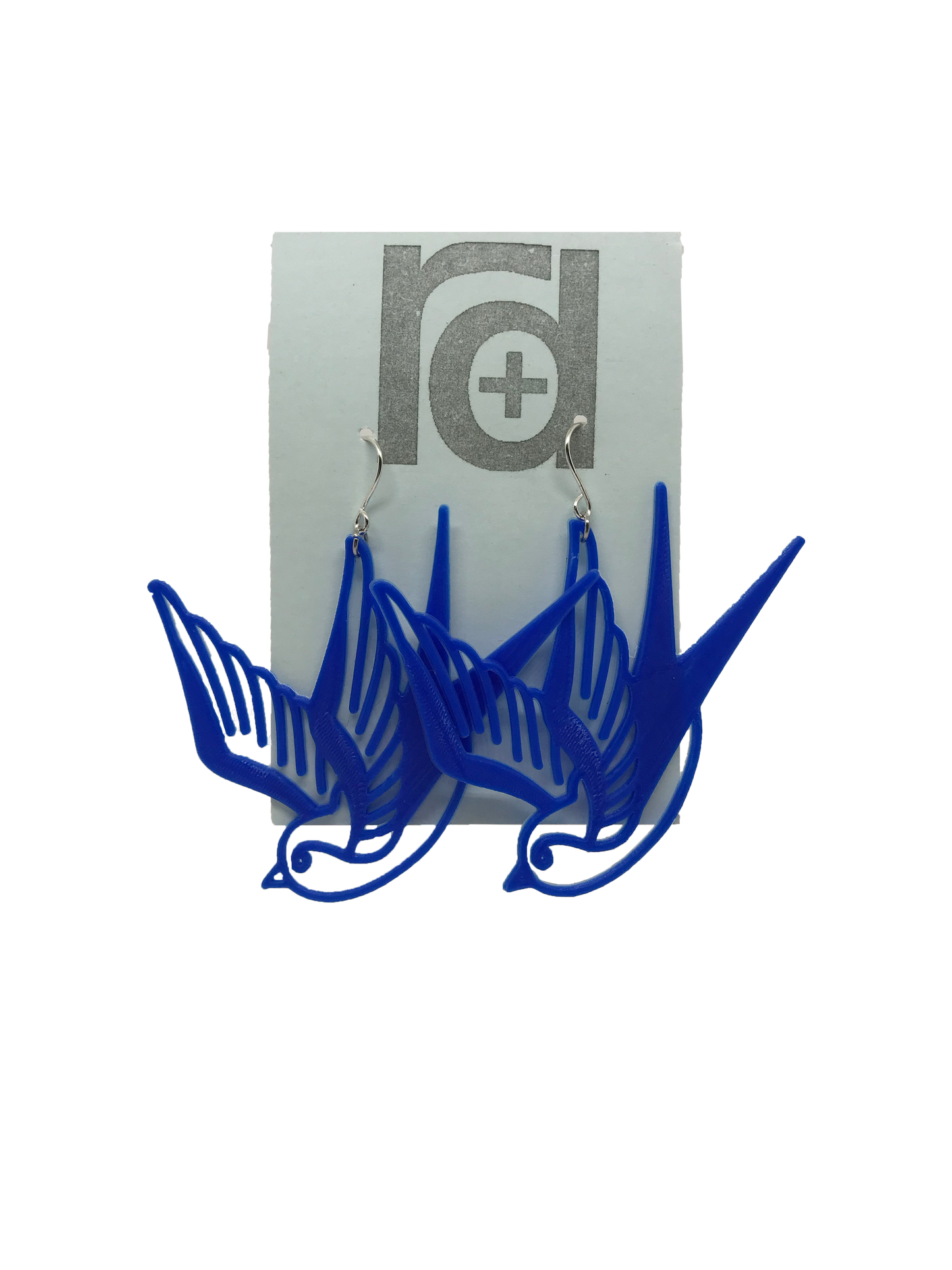On a light blue earring card are two R+D earrings. They are a classic cobalt blue and look like two swallow birds that are circling or flying down.