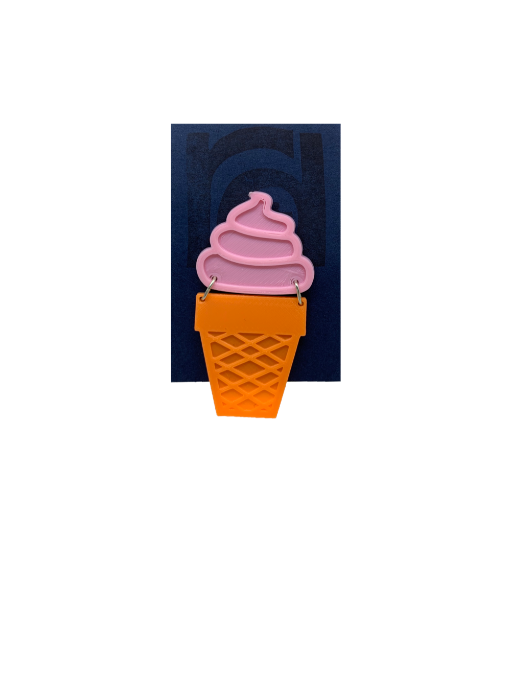A sustainably packaged pin that looks like a soft-serve ice cream cone.  The top is a solid pin swirl with a orange sugar cone hanging below. 