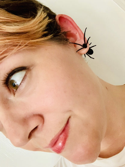Rebekah Thornhill models one of these spider earrings. They are black front and back or jacket earrings. The front piece is the head, pinchers, and four legs of a spiders body. The back part is the other four legs and a rounded spider body. The effect is that it looks as though the spiders are crawling through her earlobe.