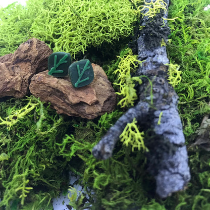 There is a lot of moss, sticks, and chips of wood. Resting in the middle are two R+D earrings. These 3D printed earrings are olive green with kelly green veins.