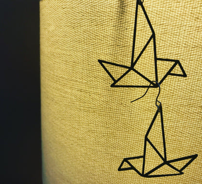 Hanging from a glowing lamp are two geometric bird earrings  in black from R+D.