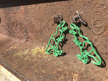 Hooked over two rusted bolts are two R+D earrings. The earrings are 3D printed in the shape of tyrannosaurus Rex or T-rex. In this picture they look like they are sparing with one another. And although they were known as meat eaters, these dinos are made from plants.