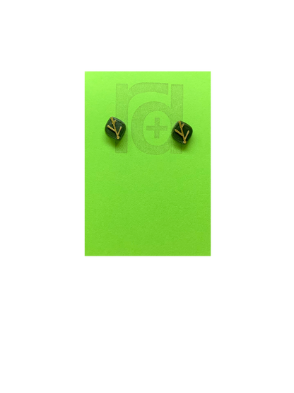 On a bright green earring card are 2 studs shaped as leaves. Each leaf is a olive green color and has veins that are gold. Not only do theres 3D printed earrings look like plants, they're made from them!