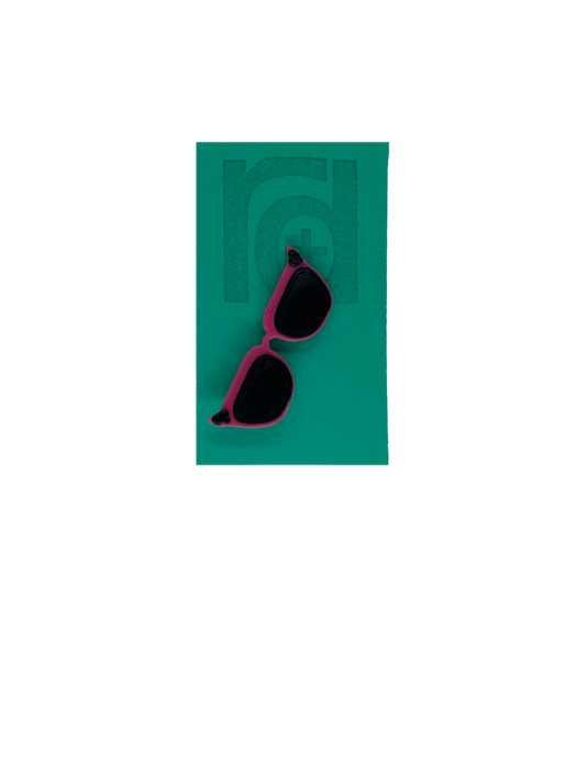 On a teal card is a R+D 3D printed pin. They're in the shape of cat eye sunglasses and have hot pink frames, black lenses, and black accents at the top corners of the glasses. 