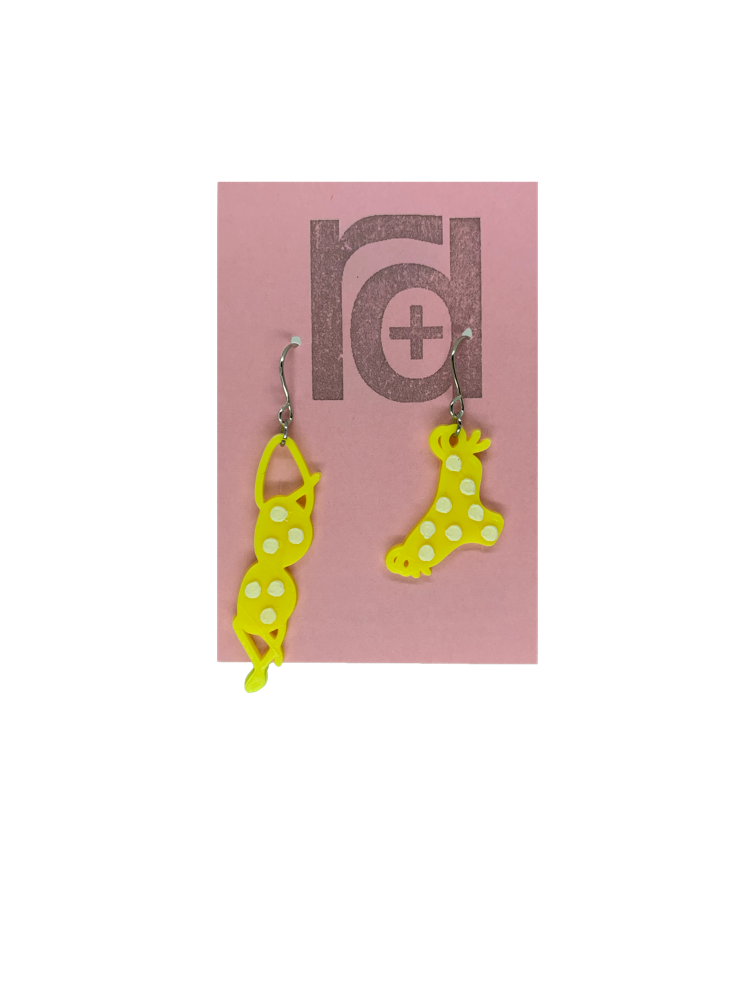 Hanging off of a pink earring card are two R+D earrings. They are asymmetrical  earrings shaped like a classic bikini  that is hung out to dry. The bottoms have ties on the sides. They are yellow with white polka dots to match the classic song, teeny tiny yellow polka dot bikini